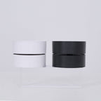 Two cylindrical lamp, one white and one black, on a light gray background.