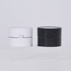 Two cylindrical lamp, one white and one black, on a light gray background.