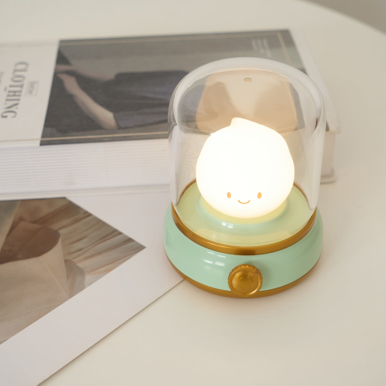 Small round night light with a smiling face on a surface with a magazine in the background