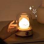 Cute lamp with a smiling face inside a glass dome, held by a hand on a warm-toned background.