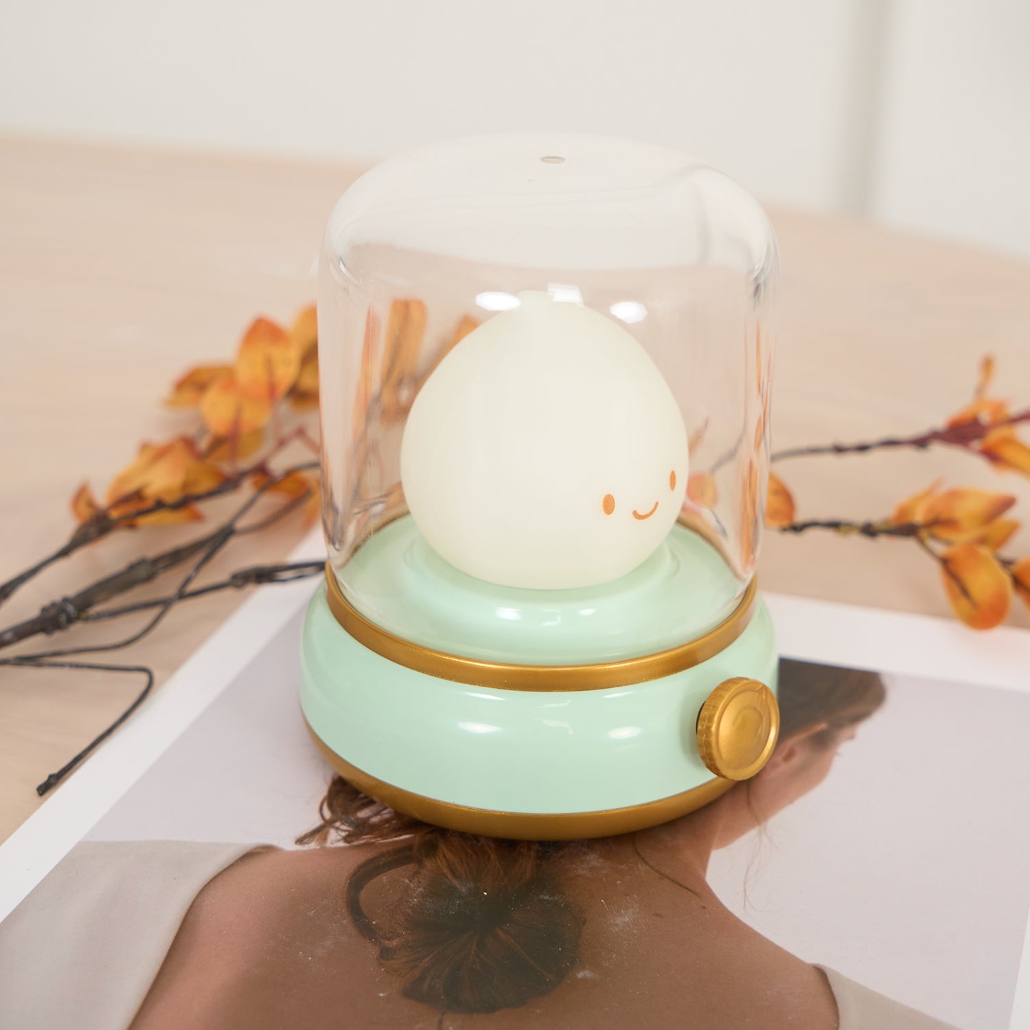 Person receiving a head massage with a device featuring a cartoon character light bulb on a blurred background.
