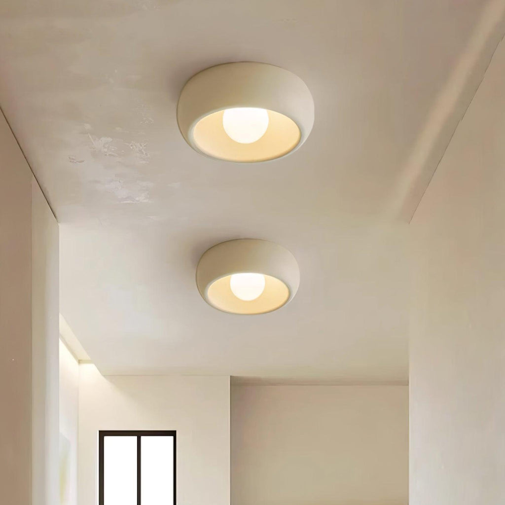 Two round ceiling lights on a white ceiling with a window and marble countertop in the background.