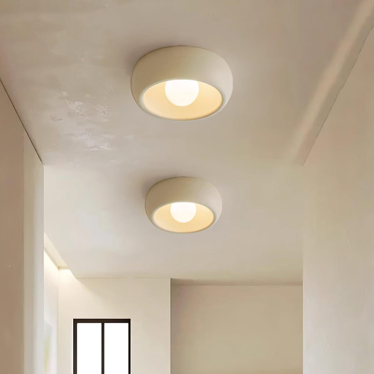 Two round ceiling lights on a white ceiling with a window and marble countertop in the background.