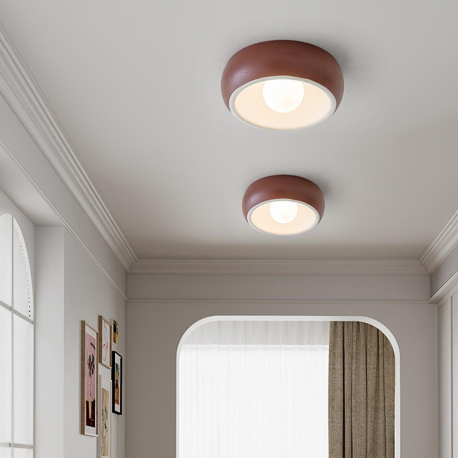Two round ceiling lights on a white ceiling with a room in the background.
