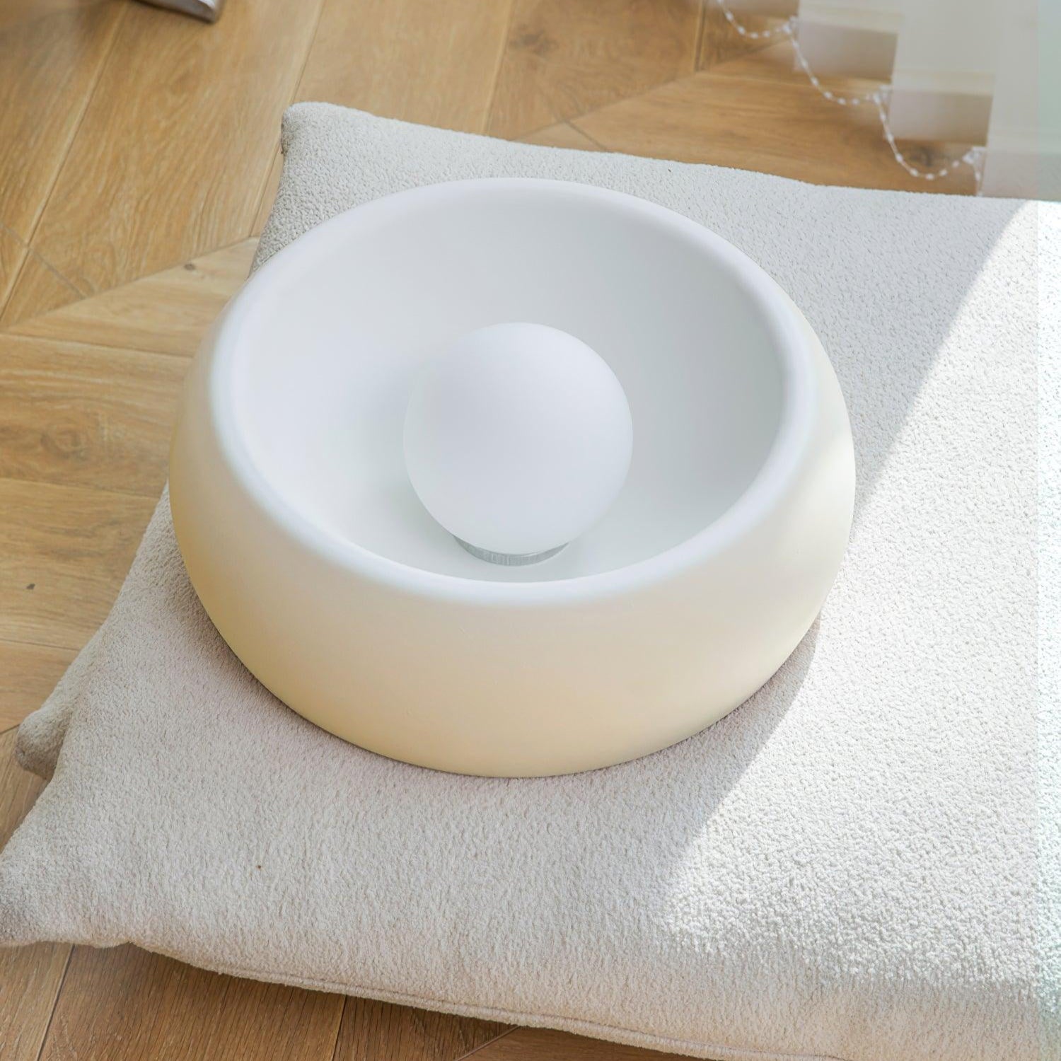 White ceramic bowl on a cushion with a plant in the background
