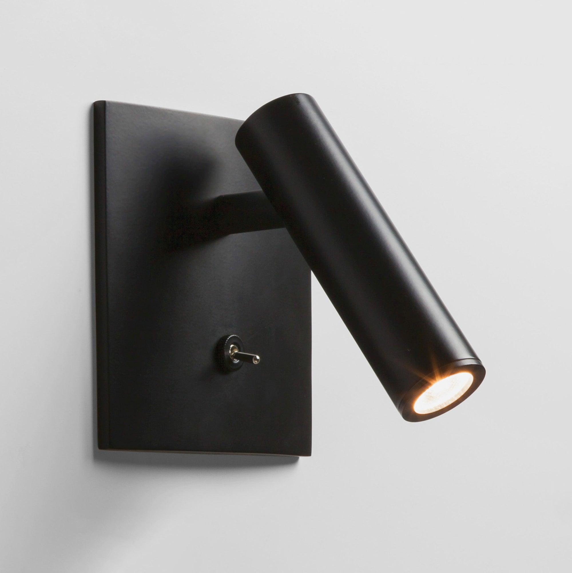 Black wall-mounted light fixture on a gray background