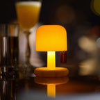 Small orange lamp on a reflective surface with blurred glasses in the background
