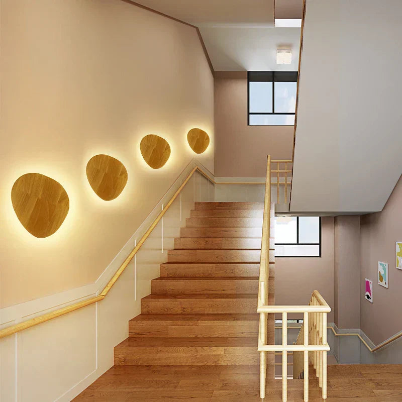 Staircase with wooden steps and wall-mounted round lights in a modern interior setting.