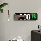 Digital wall clock with large LED display on a light gray wall.