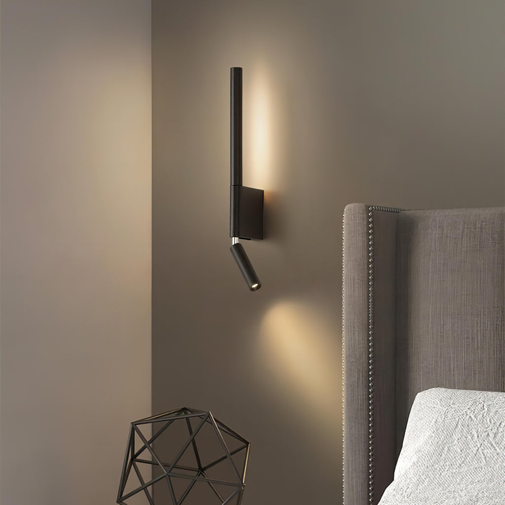 Modern wall-mounted light fixture on a gray wall next to a bed with a headboard.