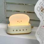 Toy toaster with a smiling face on a white surface