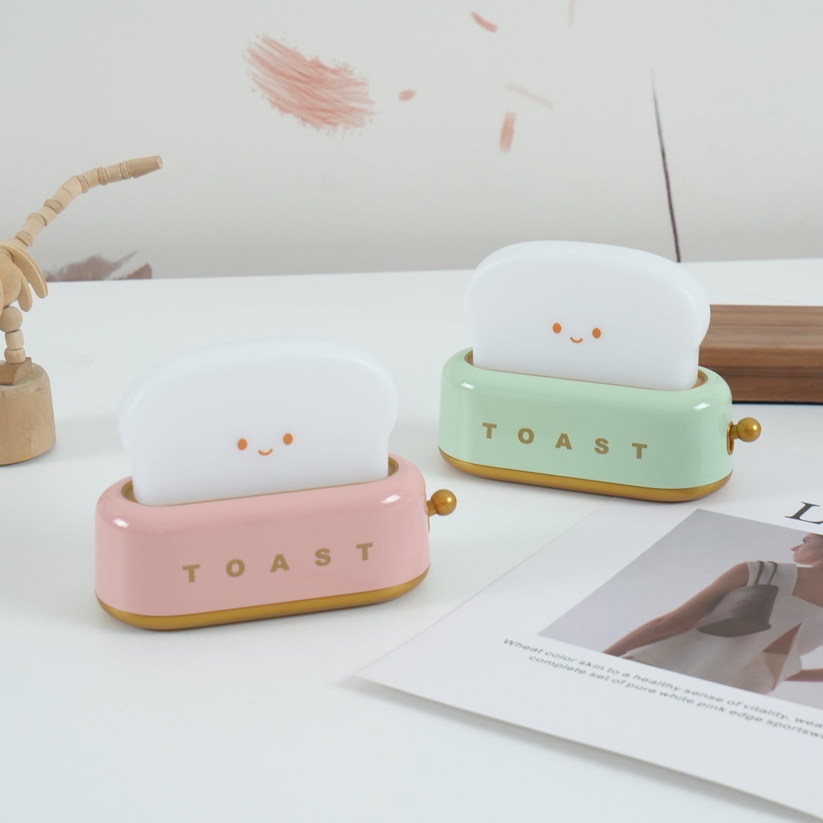 Two cute ceramic toast models on a surface with a magazine underneath.
