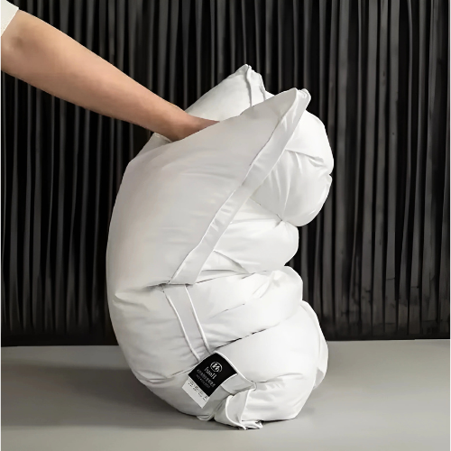 White comforter being held by a person against a dark curtain background