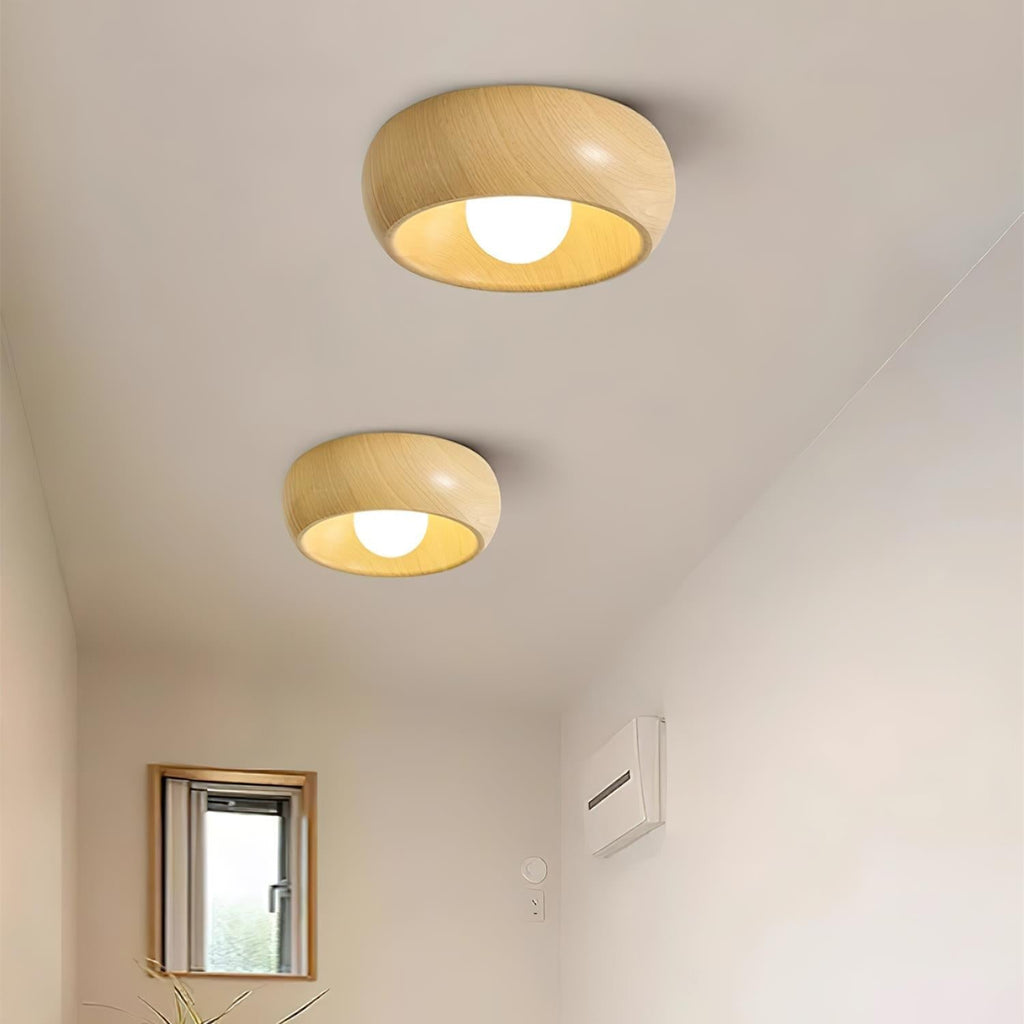 Two wooden ceiling lights on a white ceiling with a small window and plant in the background.
