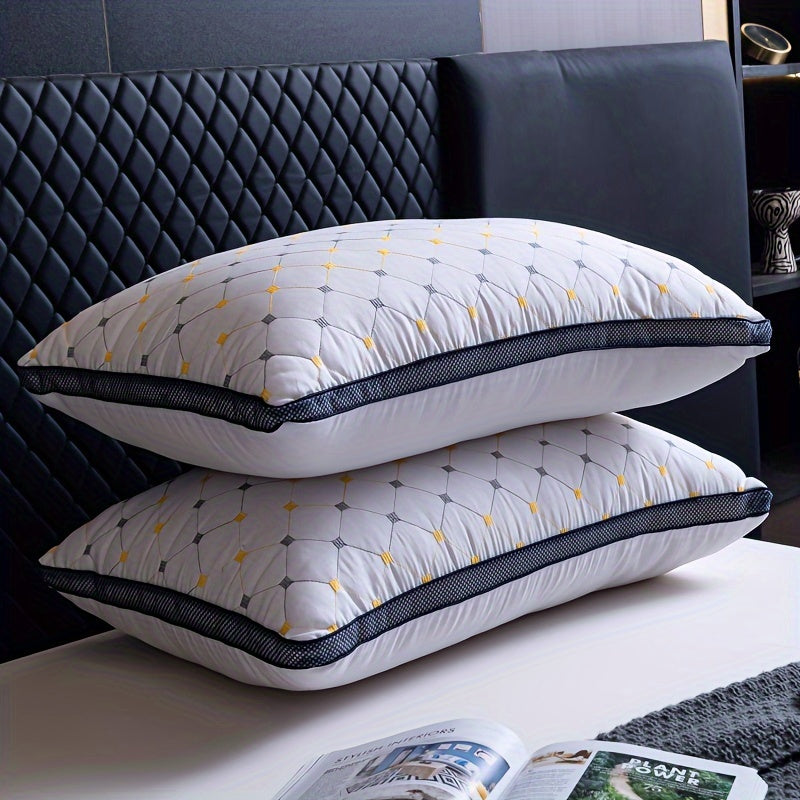 Two white pillows with black and yellow patterns stacked on a bed.
