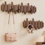 Wooden wall hooks with a handbag and headphones on a beige wall