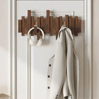 Wooden wall hook with a coat and headphones on a white door