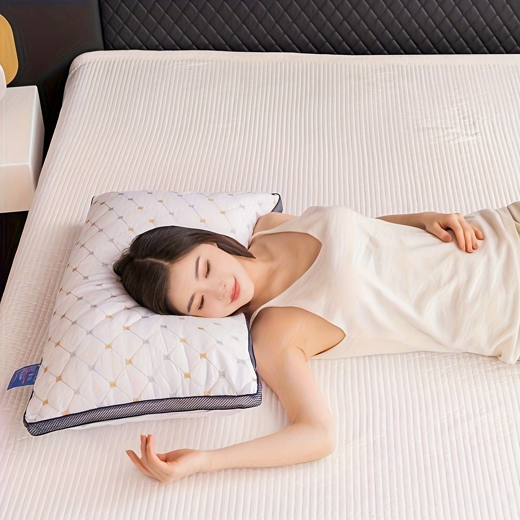 Woman lying on a bed with a pillow, wearing a white tank top.