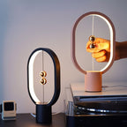 Two table lamps, one black and one pink, on a surface with a blurred background.