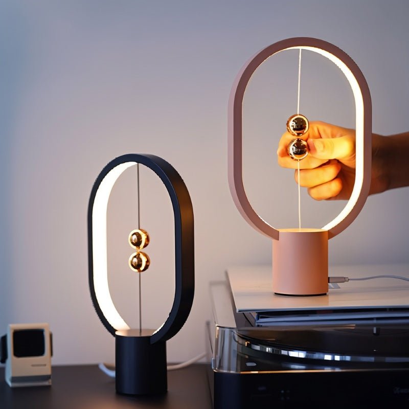 Two table lamps, one black and one pink, on a surface with a blurred background.