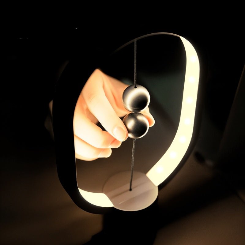 Hand holding a black and silver pendant with a dark background