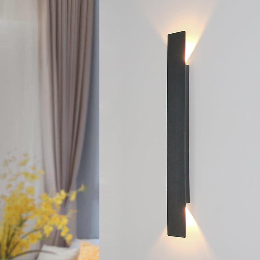 Modern black wall sconce on a white wall with a curtain and plant in the background