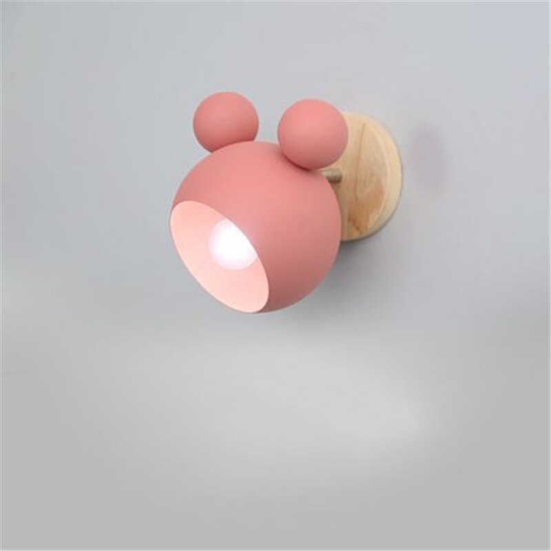 Pink wall light fixture with wooden base on a gray background
